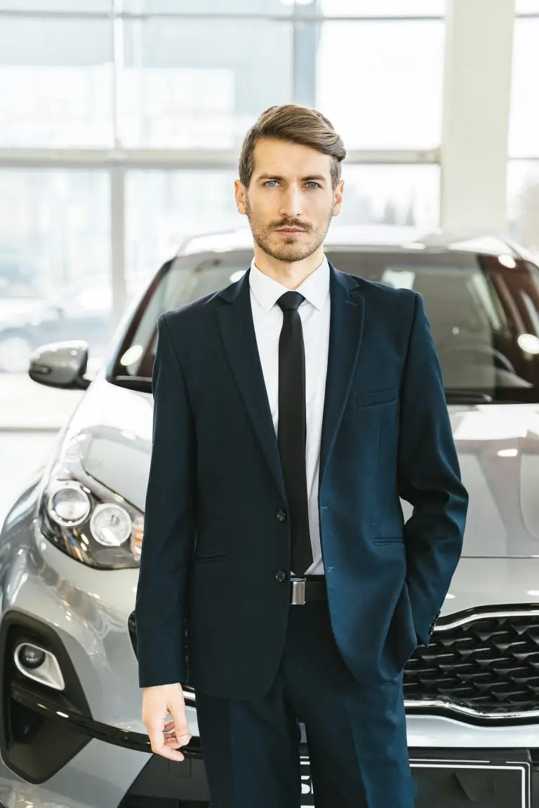 Car salesman standing in showroom in front of a car